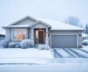 Winter exterior of a detached home in Edmonton with snow on the roof and yard under an overcast sky.
